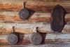 Cast iron pans hanging on the interior wall of a wood log cabin.