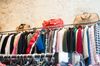 A rack of brightly coloured clothing with some weekender bags on top
